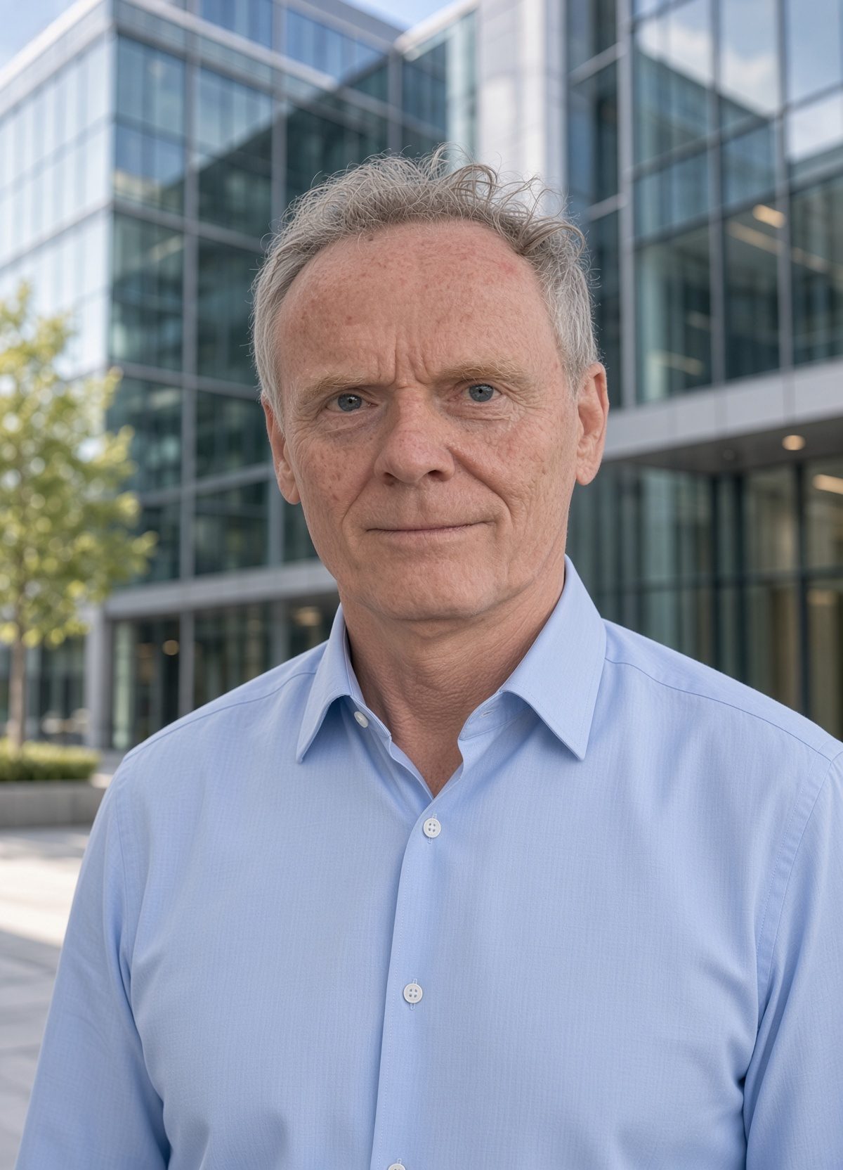 Oscar Jager, Energieberater, im hellblauen Hemd vor einem modernen Bürogebäude mit Glasfassade